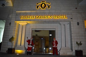 Exterior do Hotel Golden Taybeh, com uma entrada imponente e duas figuras do Papai Noel em frente.