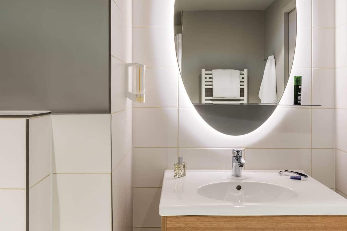 A modern bathroom with a white sink, a mirror, and a towel rack.