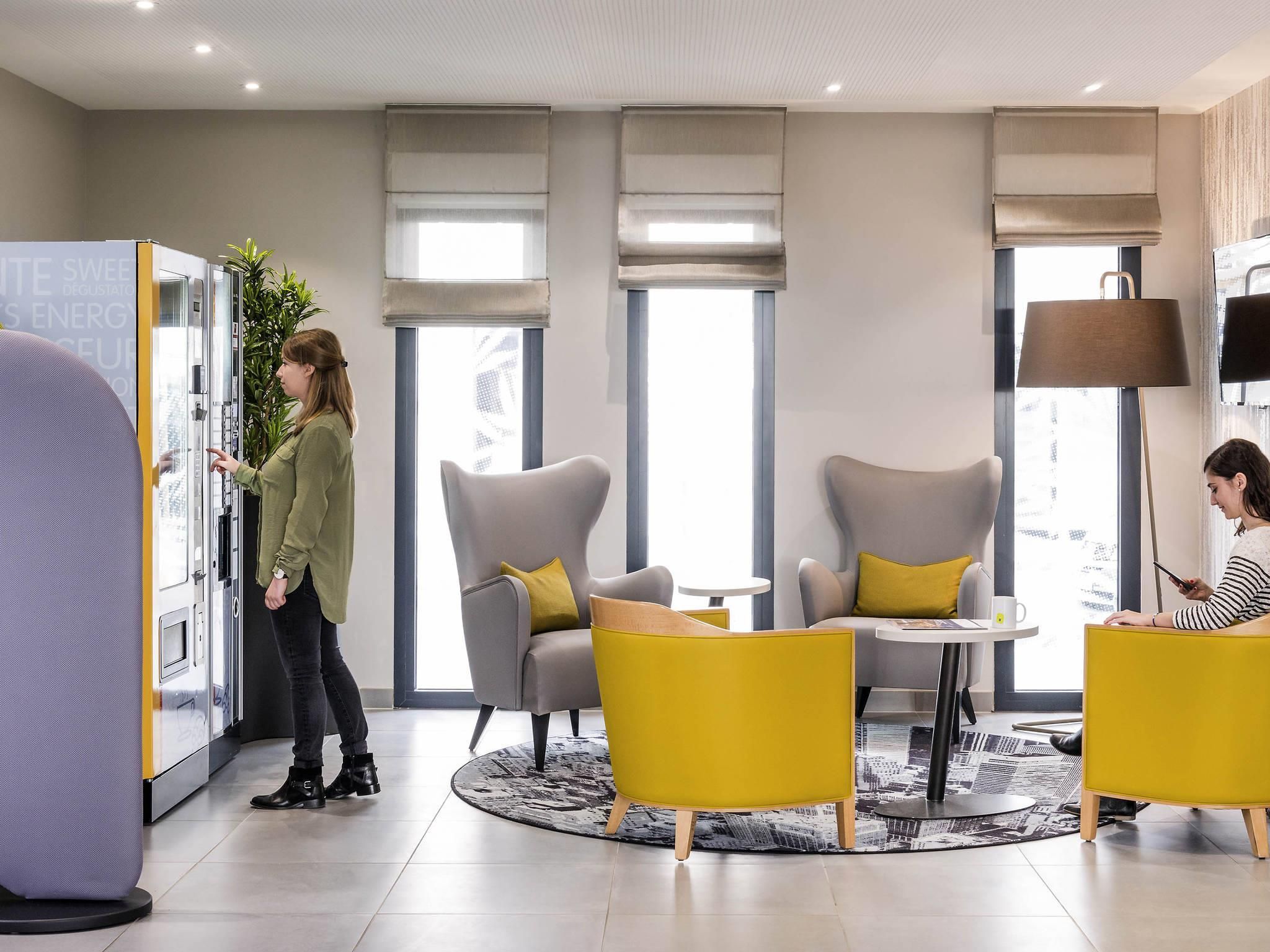 Rebedor d'hotel modern amb zones d'estar, una finestra gran i una màquina expenedora.