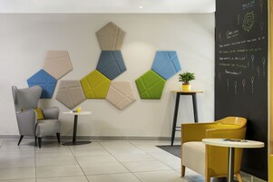 Un moderno vestíbulo de hotel con arte mural geométrico, dos mesas redondas y sillas contemporáneas.