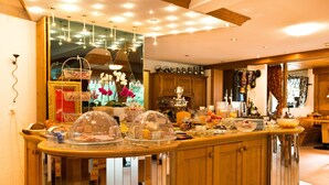 Un comptoir-repas bien éclairé, où l’on trouve une variété d’aliments et de boissons, ainsi que des armoires en bois et un miroir qui reflète la pièce.