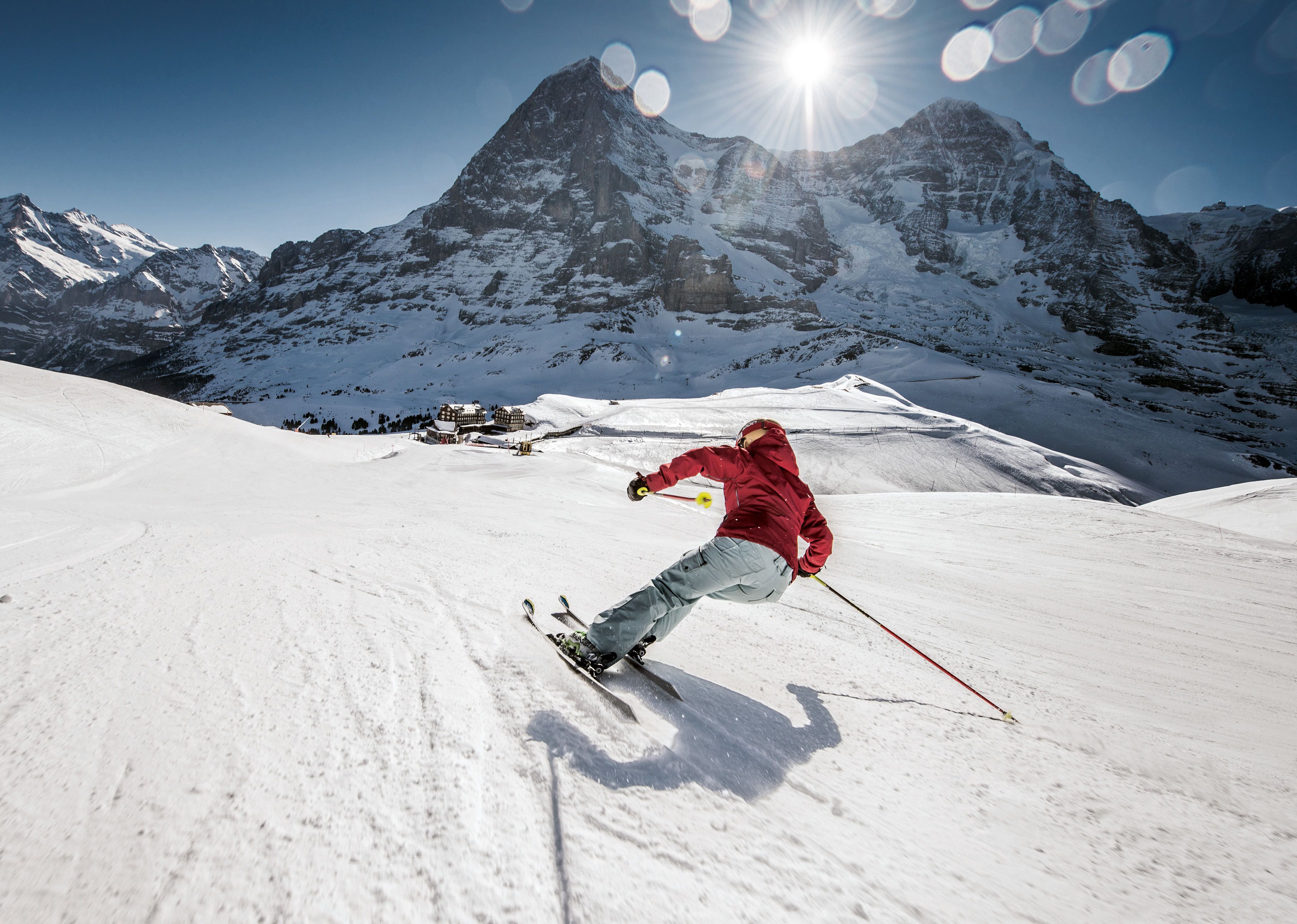 A skier on a snowy slope with a mountain in the background.