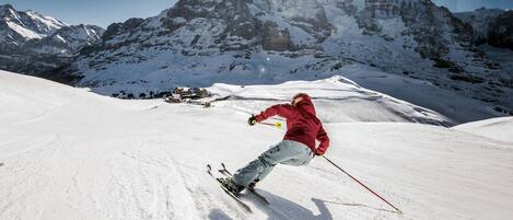 A skier on a snowy slope with a mountain in the background.