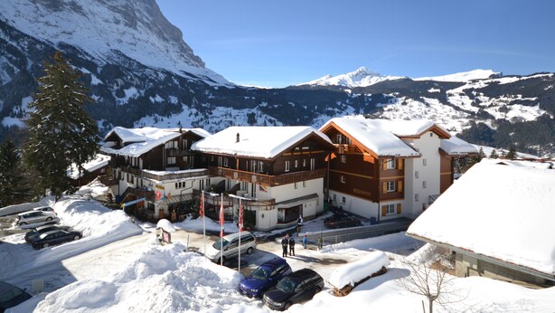 Un hôtel à étages, avec des toits enneigés et un paysage montagneux en arrière-plan.