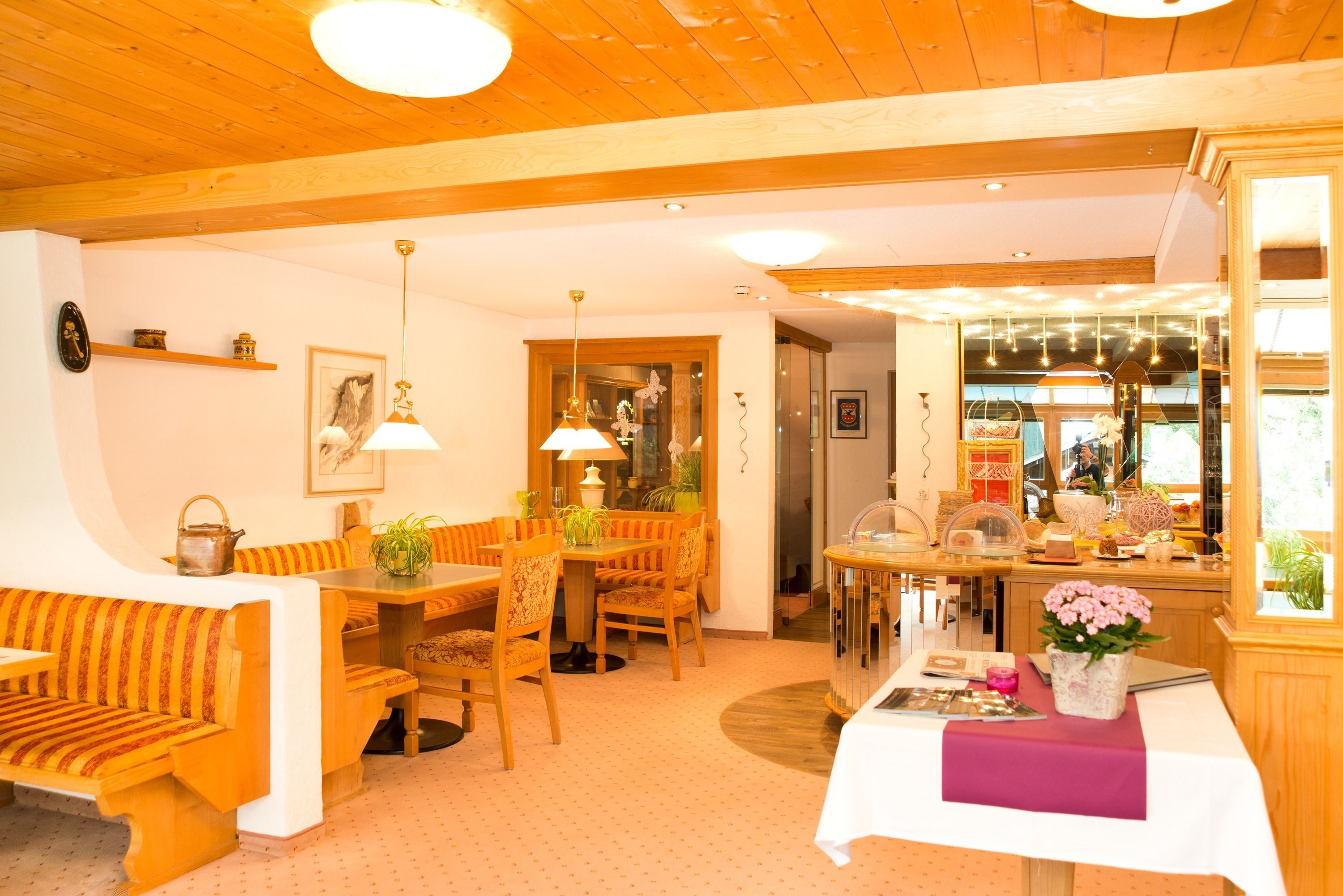 Ein gemütlicher Essbereich mit Holzmöbeln, einem Tisch mit Blumenvase und einer Holzbalkendecke.