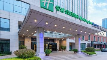 A hotel entrance with a modern design, featuring a covered entrance area, glass railings, and a sign with Chinese characters.