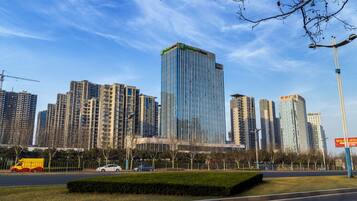 A cityscape with modern high-rise buildings, a clear sky, and a well-maintained urban park area.