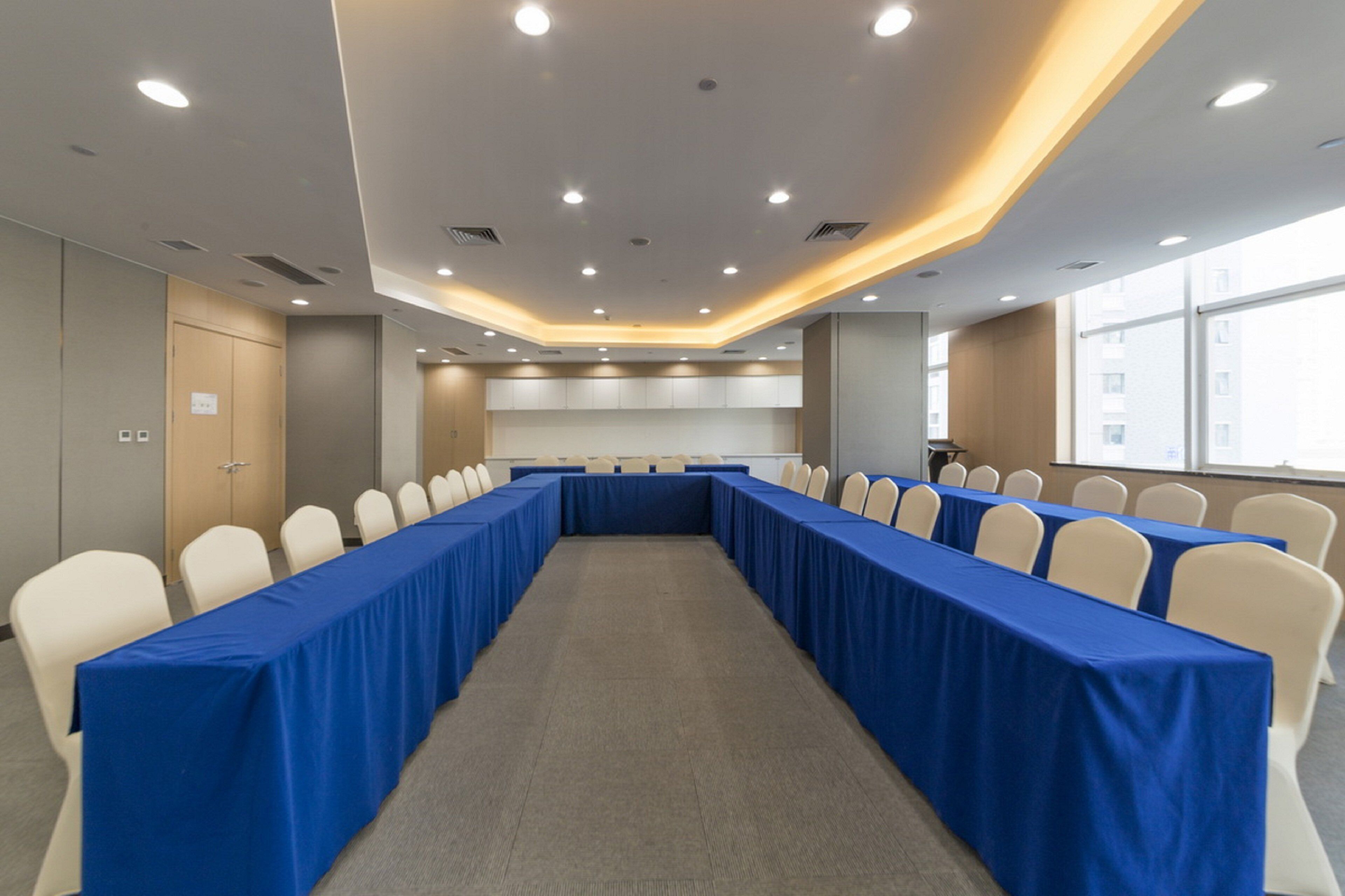 A conference room with a long table, white chairs, and a carpeted floor.