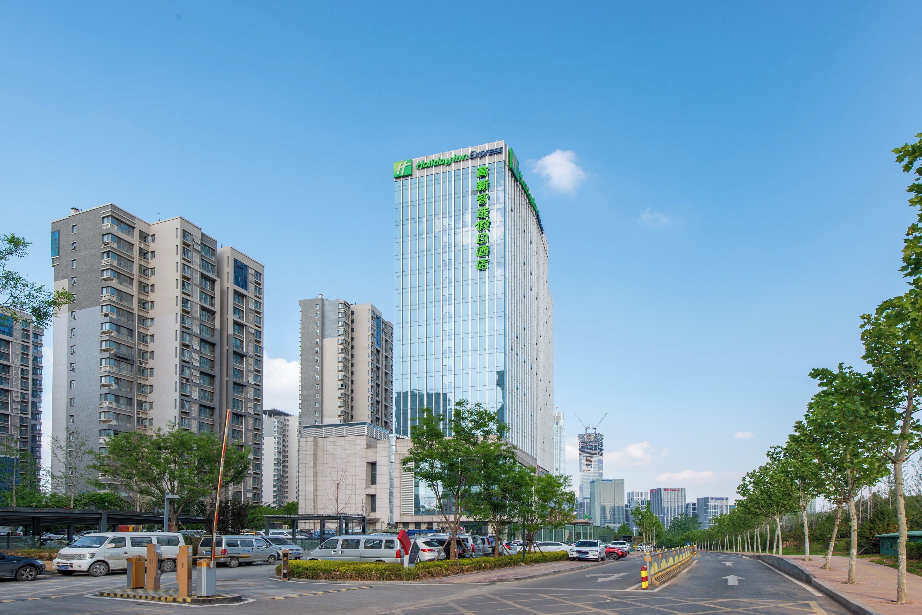 A modern high-rise hotel with a glass facade, surrounded by other buildings and a clear sky.