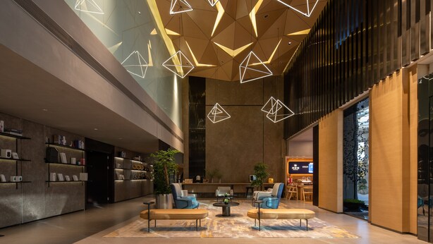 Un hall d’entrée moderne, doté de luminaires aux formes géométriques, d’espaces aménagés pour s’asseoir et d’un comptoir d’accueil.