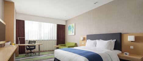 Ein Hotelzimmer mit Bett, Schreibtisch, Stuhl und Blick ins Freie.