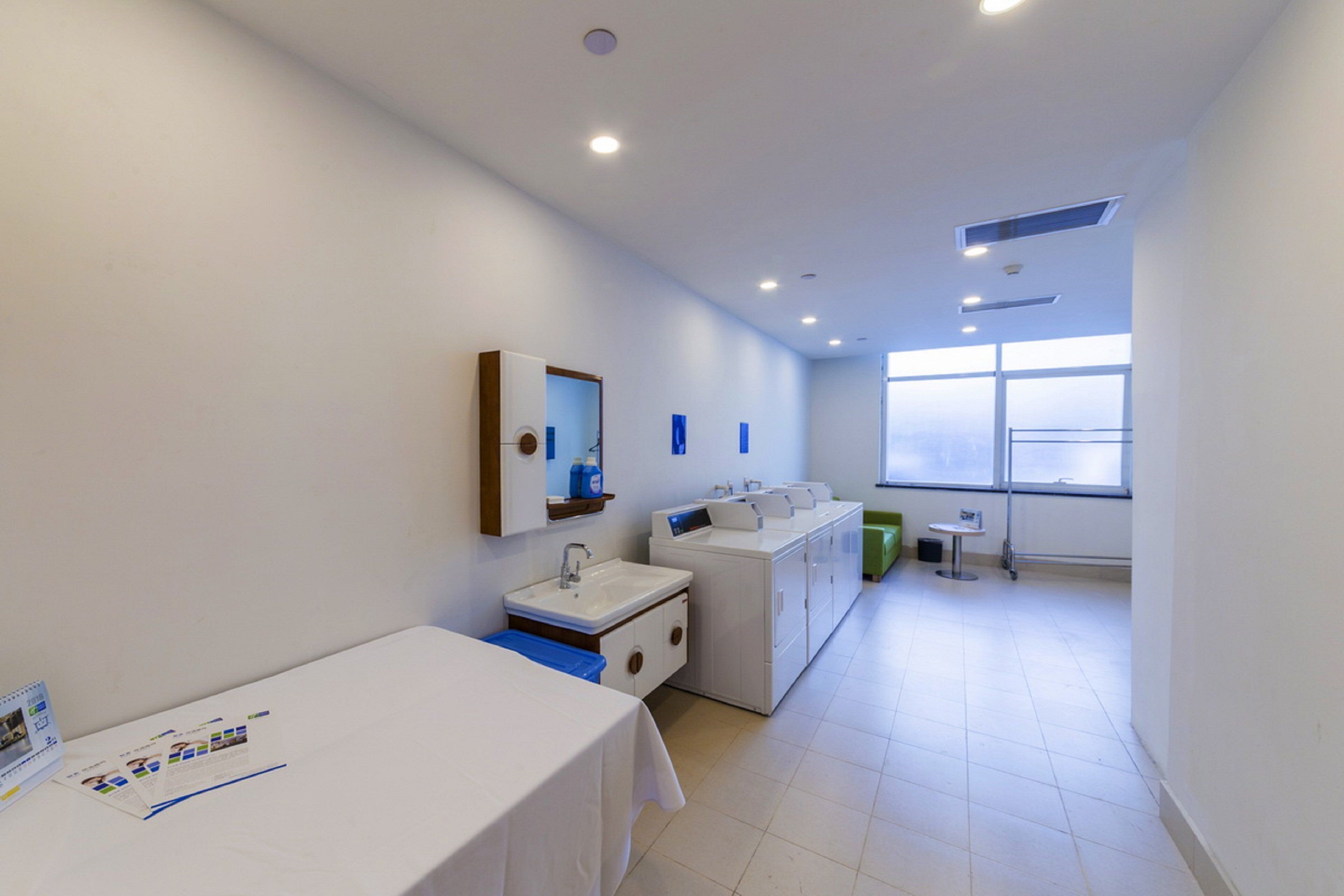 A modern bathroom with a sink, mirror, and a table with brochures.
