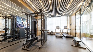 Une salle de sport équipée de matériel d’exercice, d’un tapis de course et d’un écran de télévision.