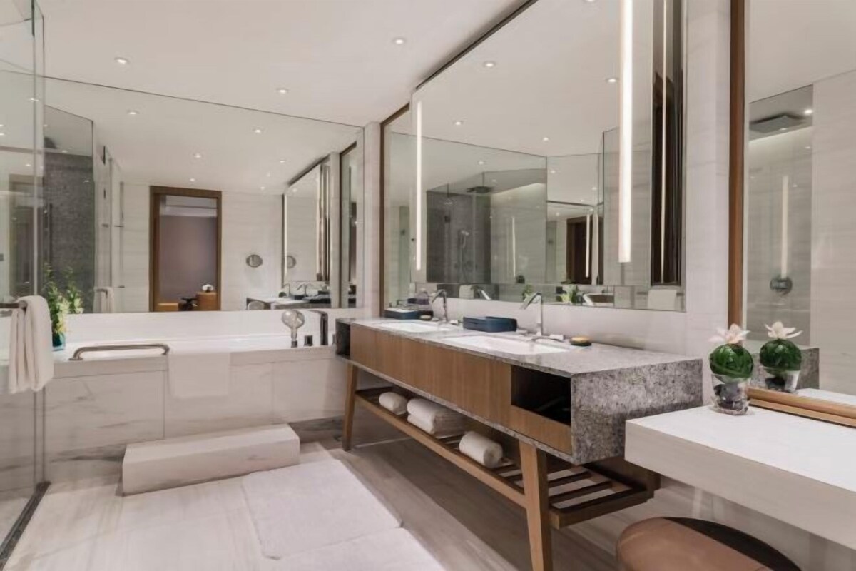 A modern bathroom with a large mirror, a bathtub, and a vanity with a sink.