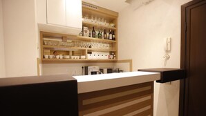 A kitchen with wooden shelves holding glassware and bottles, a coffee maker, and a phone on the wall. - City Code Exclusive (Belgrade)
