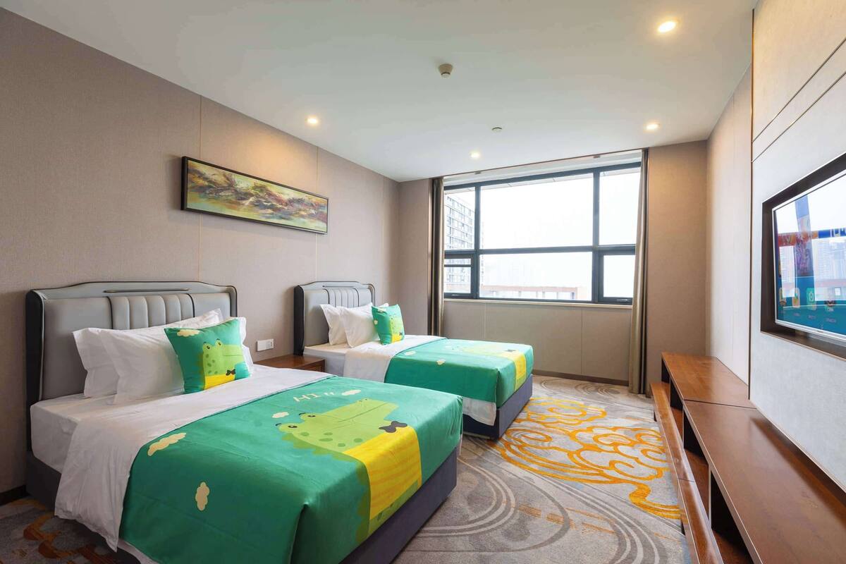 A hotel room with two beds, a large window, a painting on the wall, and a television on the wall.