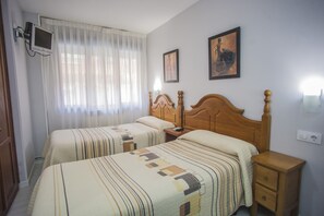 A hotel room with two beds, a TV mounted on the wall, and two paintings on the wall. - Hostal Santa Barbara (Soria)