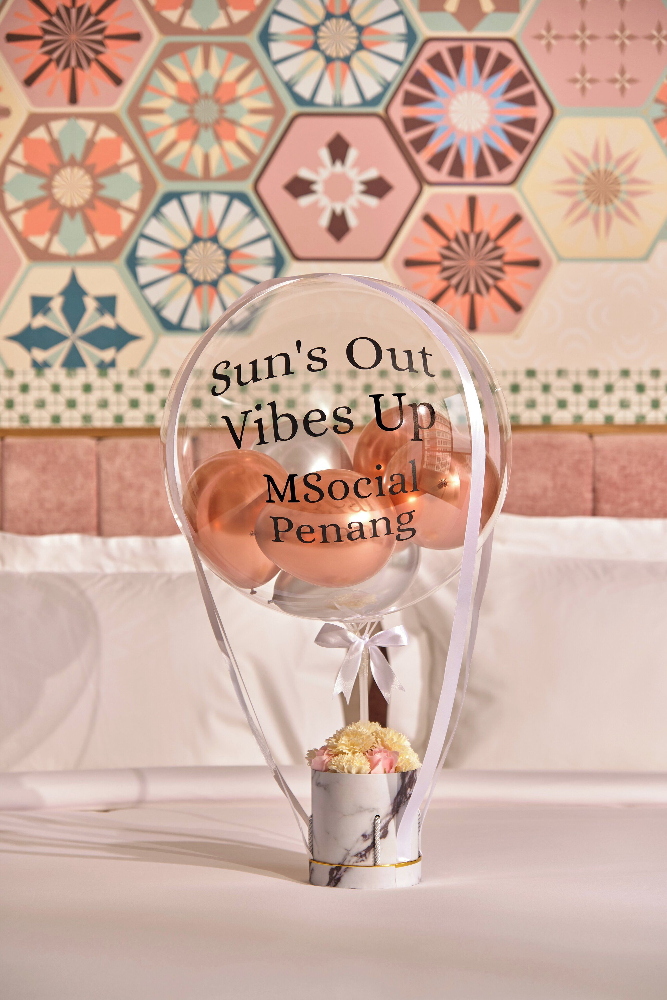 A clear balloon with text and a small bouquet of flowers.