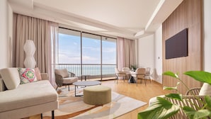 A modern living room with a sofa, ottoman, and dining area. - M Social Resort Penang (George Town)