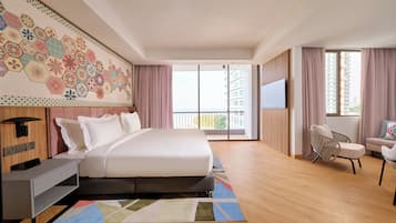 A modern hotel room with a large bed, a desk, a chair, and a TV. The room has a balcony with a view of the city.