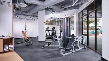 A modern gym with various exercise equipment, large windows, and a clean, industrial design.