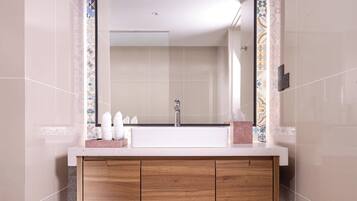 A bathroom with a white sink, wooden vanity, and a tiled backsplash.