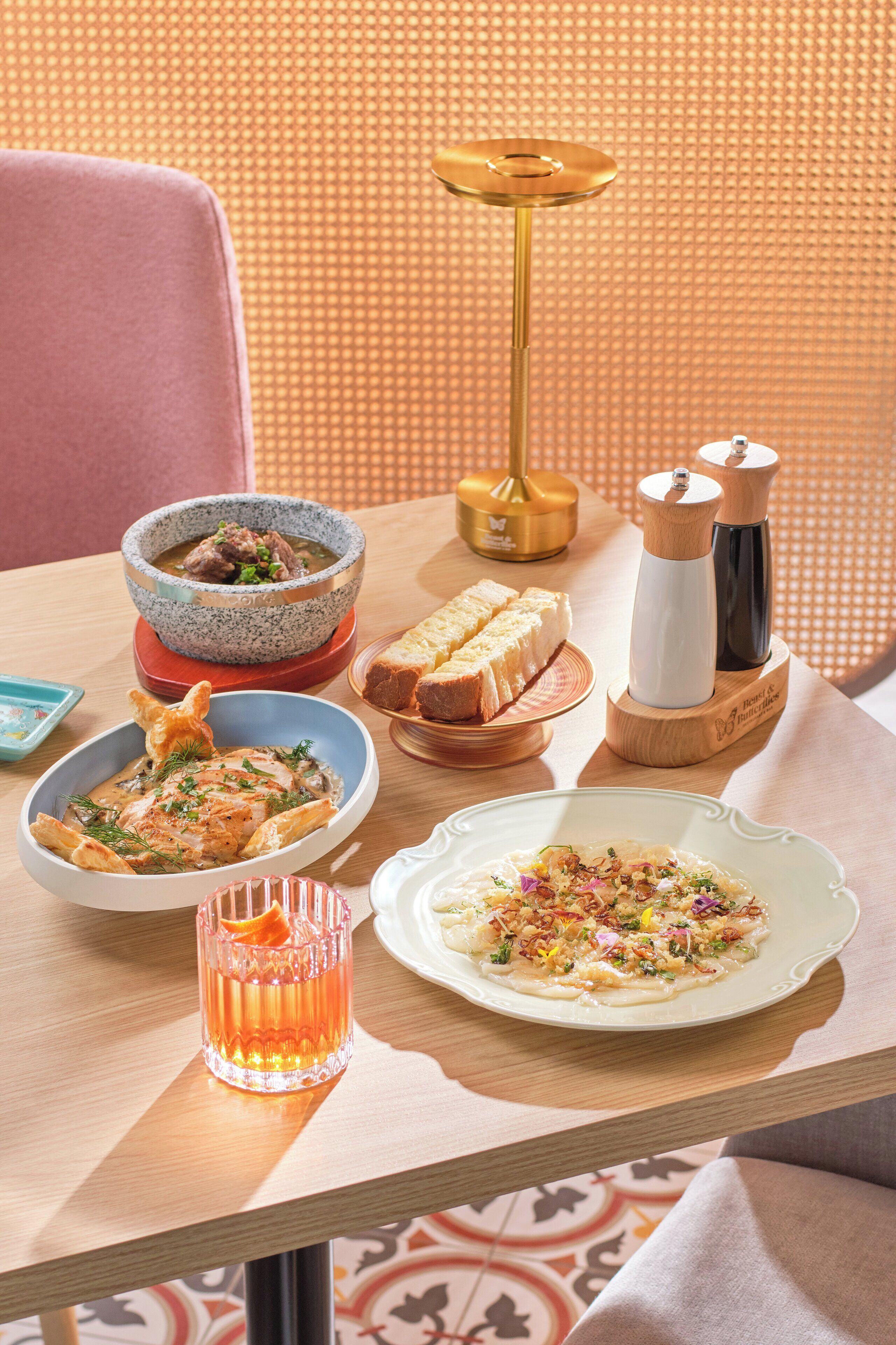 A dining table with various dishes, a glass of orange juice, a salt and pepper set, and a decorative lamp.
