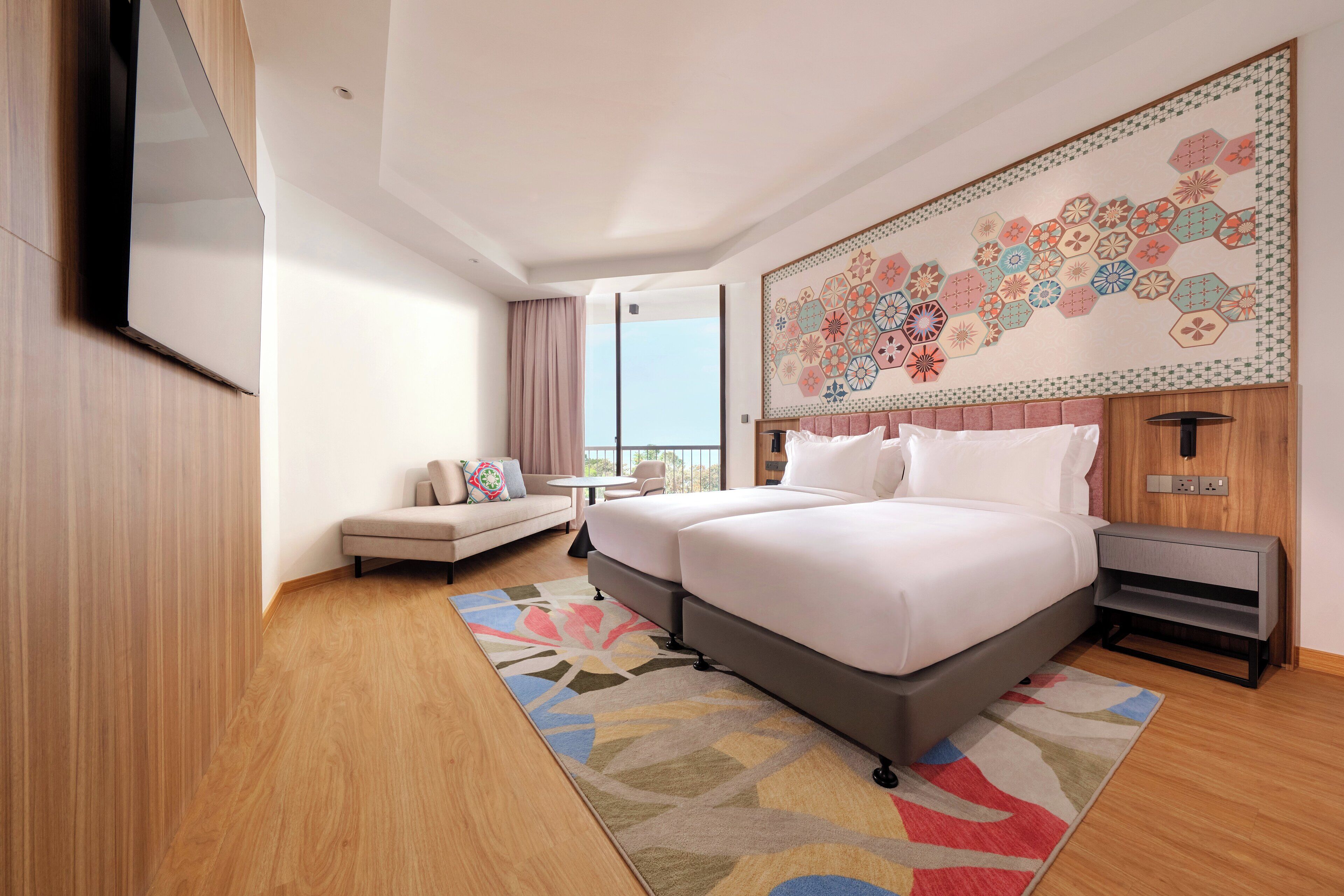 Una habitación de hotel moderna con una cama grande, un sofá, una mesita y un adorno en la pared.