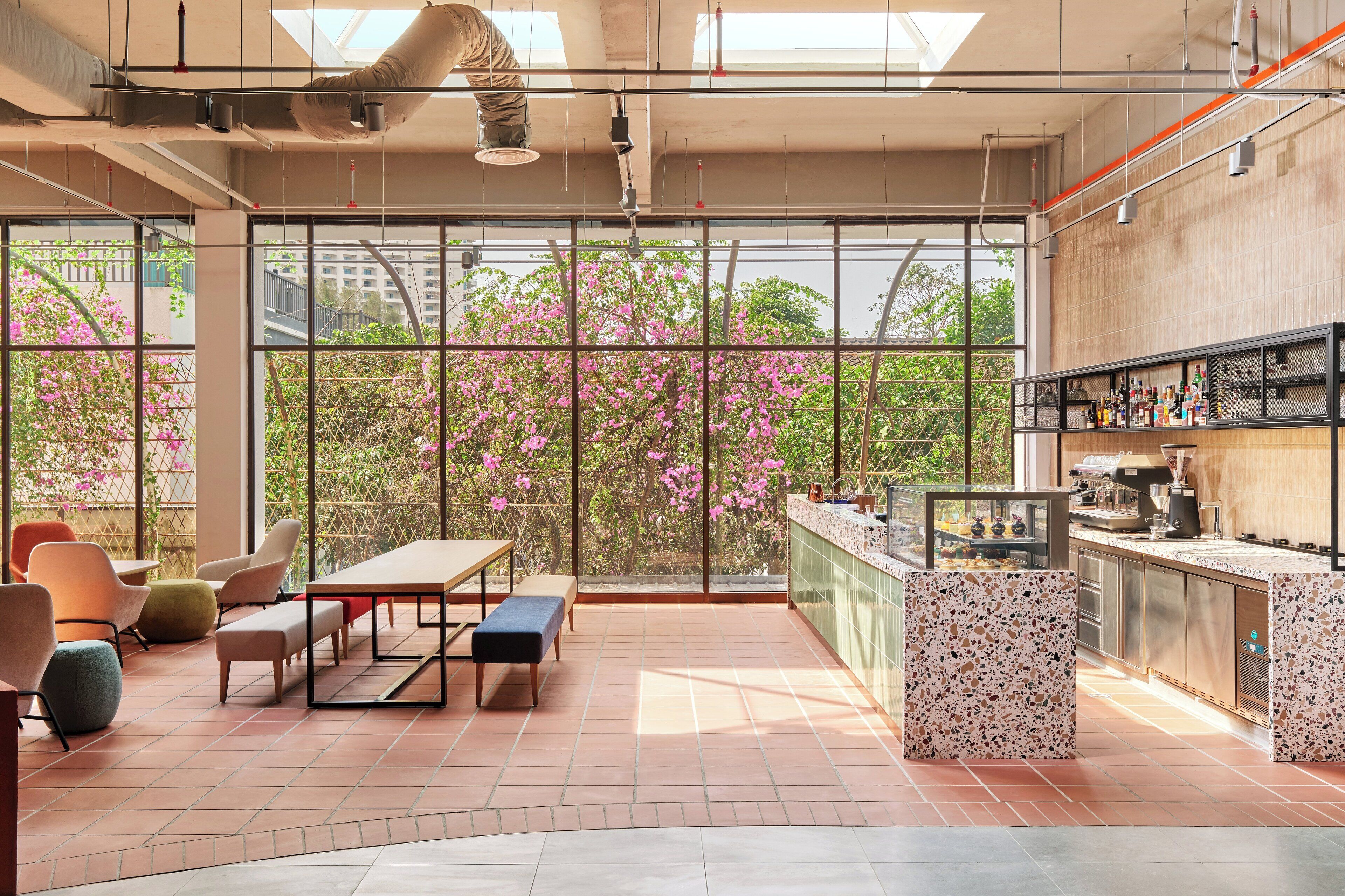 Una cocina moderna con ventanas amplias, una barra y asientos con vistas a flores rosadas.