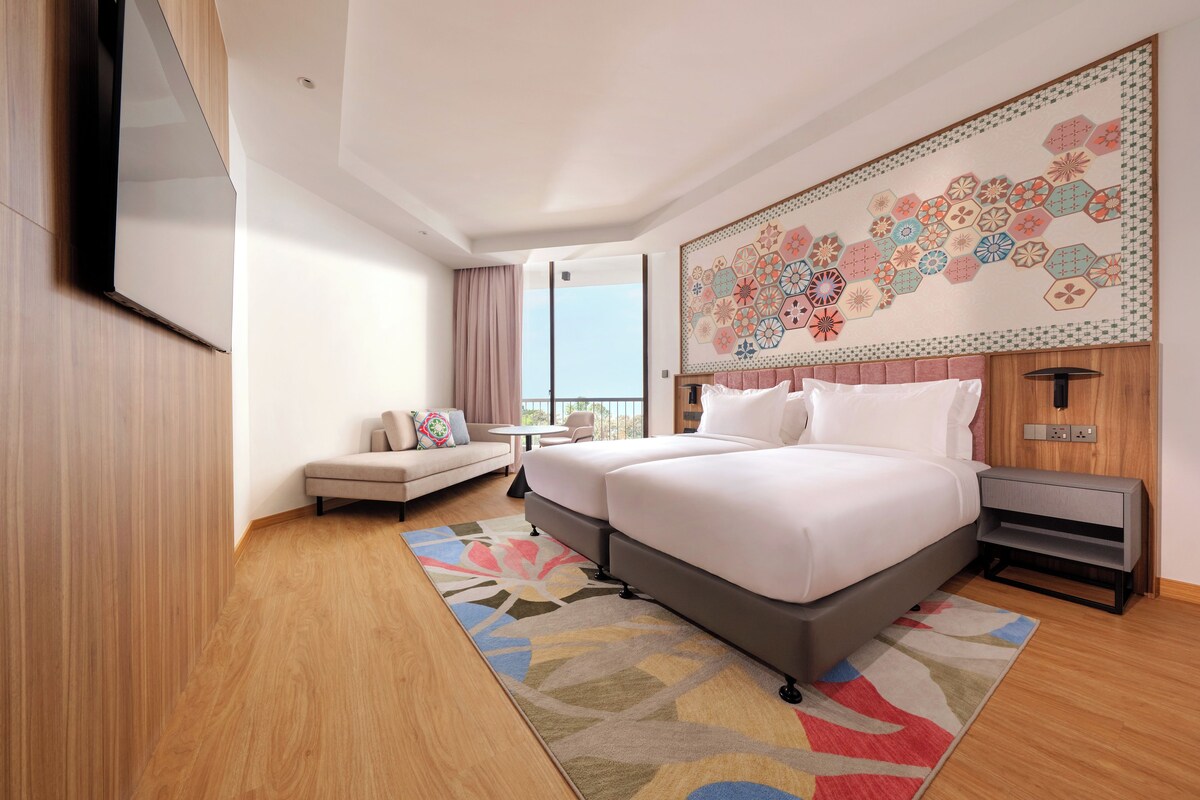 Habitación de hotel con una cama grande, un sofá, una mesita pequeña y un adorno de pared.