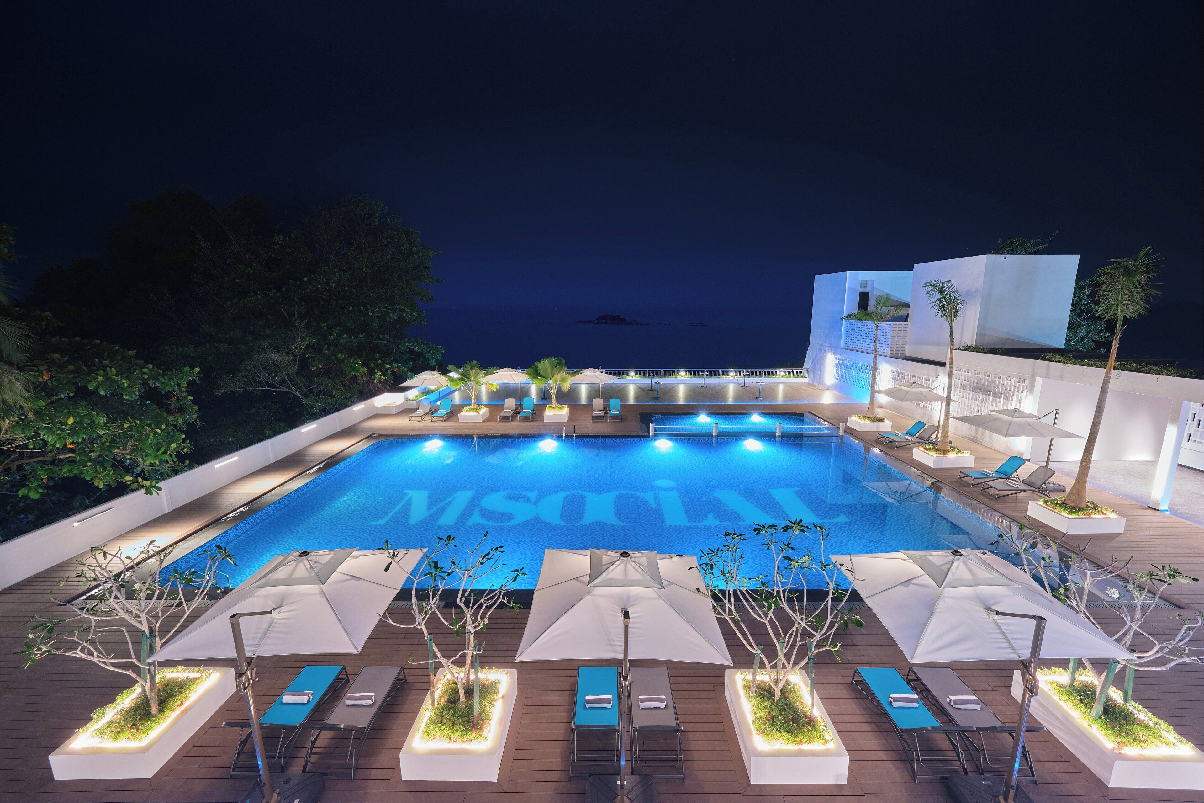 Una piscina al aire libre, sombrillas, sillones reclinables de piscina