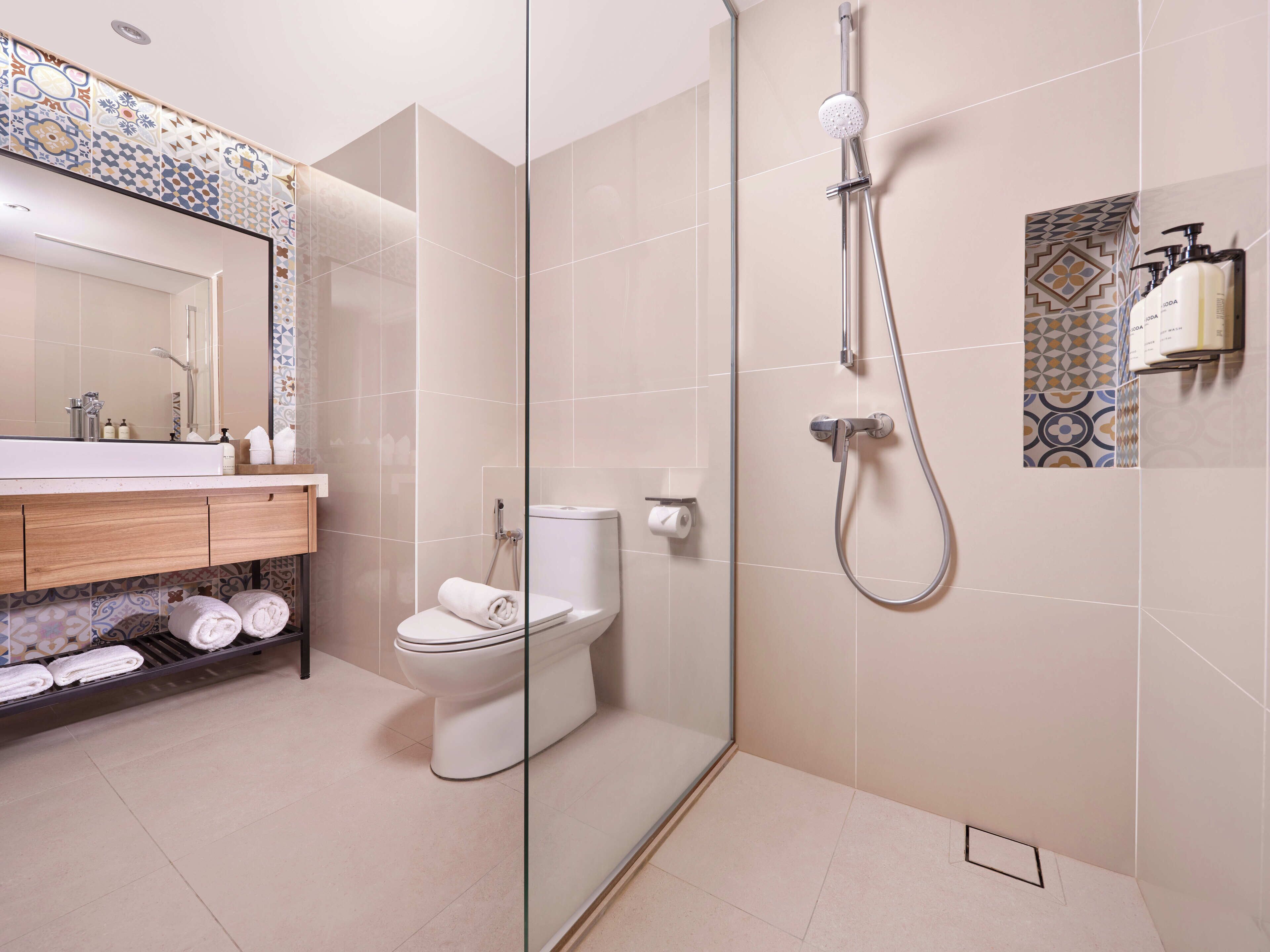 A modern bathroom with a glass-enclosed shower, a toilet, and a vanity with a mirror.