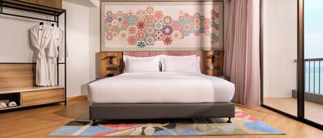 A modern bedroom with a large bed, a wooden wardrobe, a robe rack, and a decorative wall tapestry.