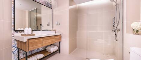 A modern bathroom with a large mirror, a wooden vanity, a shower, and a toilet.