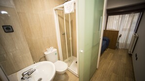 Un baño moderno con lavamanos, inodoro y cabina de ducha de vidrio.