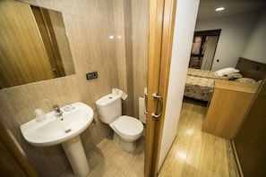 Un baño con lavamanos, inodoro y puerta de madera.