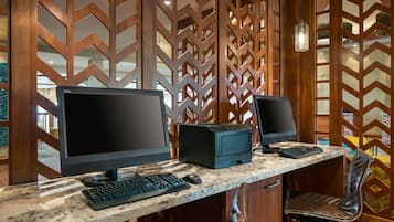 Un espace de travail équipé de deux écrans, d’un clavier et d’une imprimante, le tout posé sur un plan de travail en marbre.