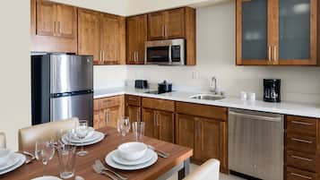 A modern kitchen with wooden cabinets, stainless steel appliances, and a white countertop.
