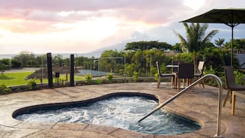 A hot tub with a view of the ocean and a sunset.