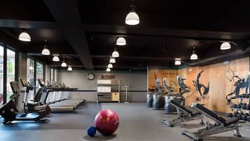 A gym with treadmills, elliptical machines, free weights, and exercise balls.