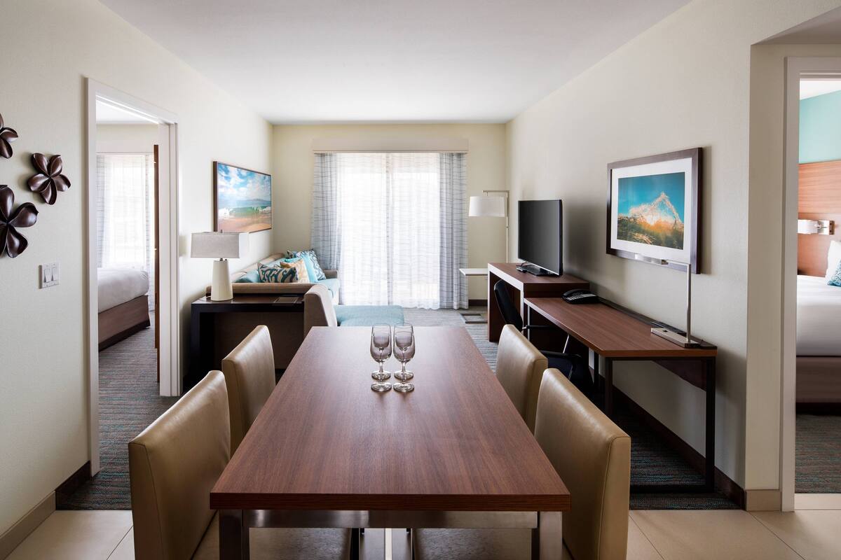 A hotel room with a dining area, a TV, and a bed.