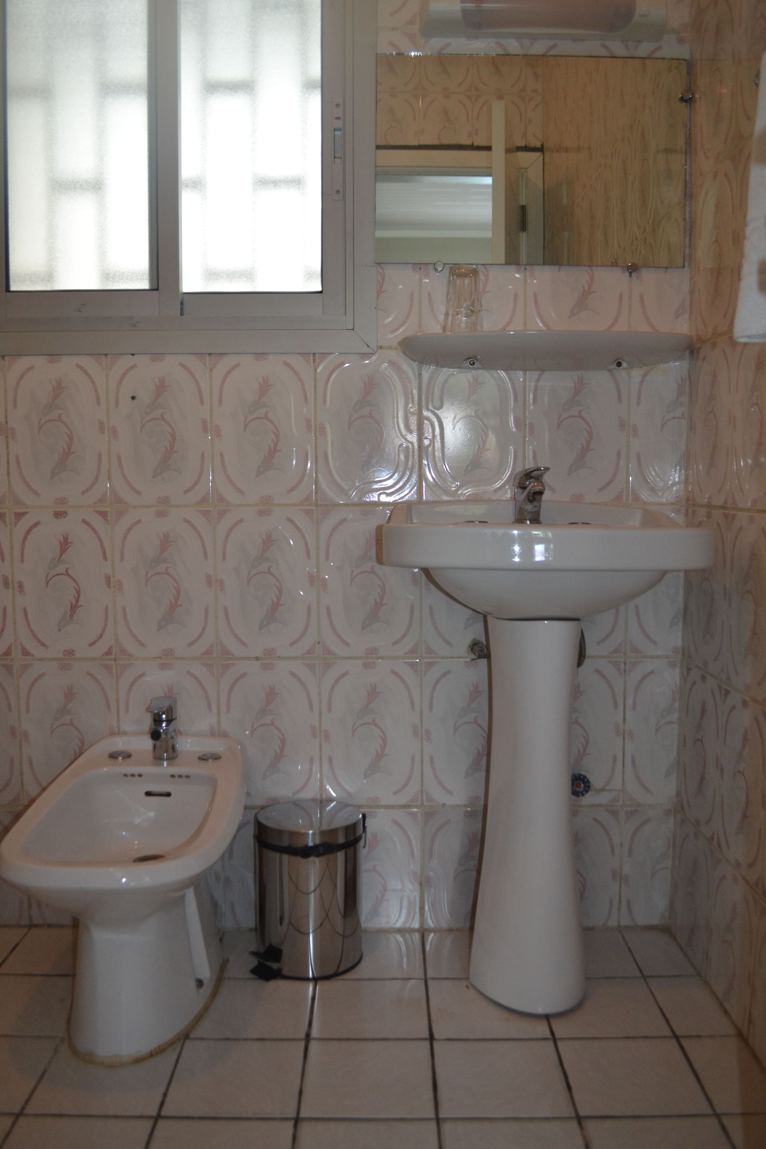 A bathroom with a bidet, sink, and mirror.