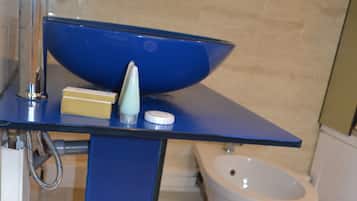 A bathroom with a blue sink, a white toilet, and a trash can.