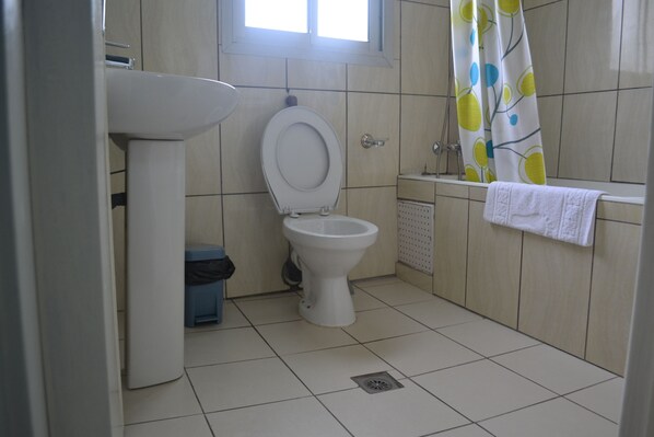A bathroom with a toilet, sink, and shower curtain. - Hôtel La Falaise Bonanjo (Douala)