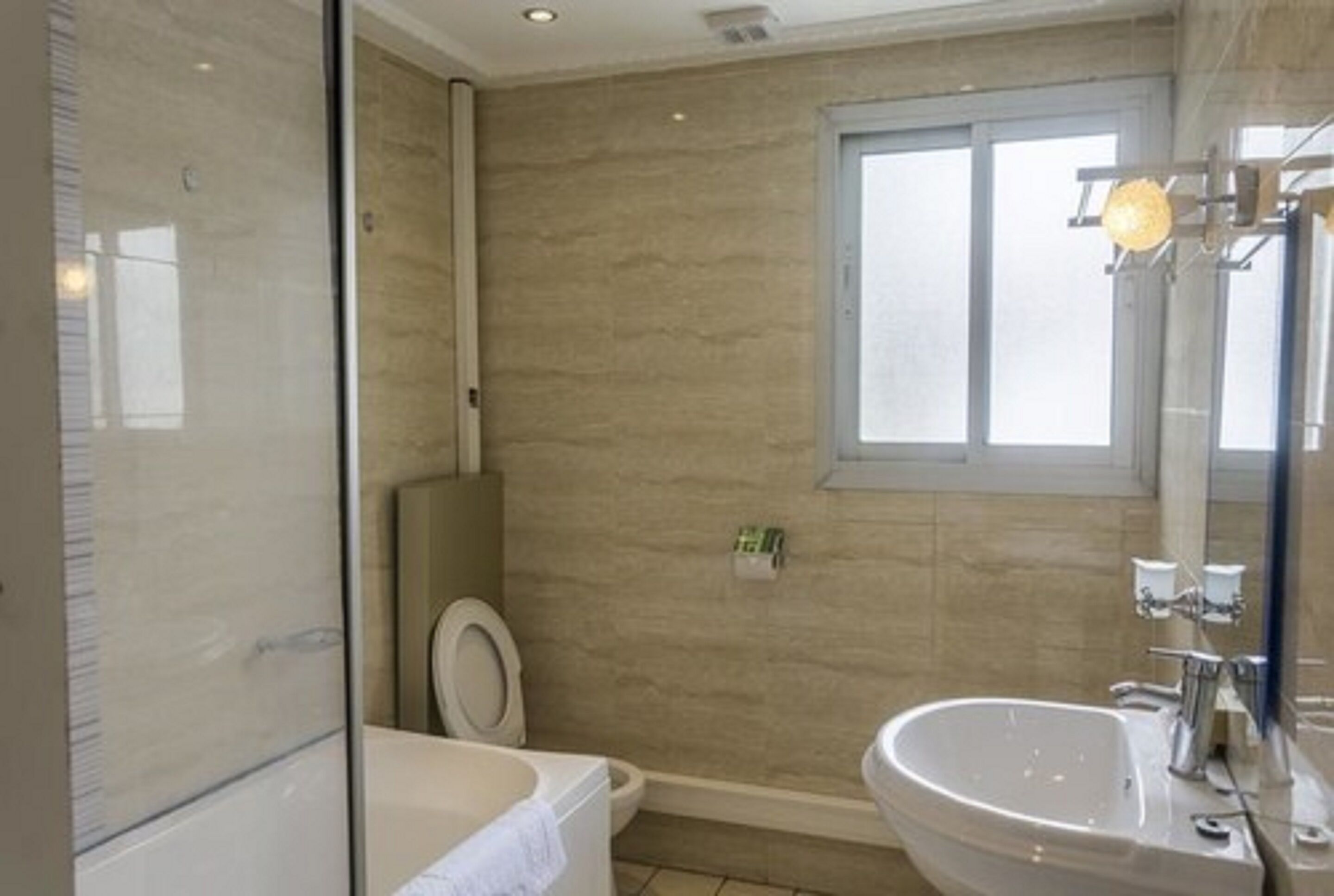 A modern bathroom with a bathtub, sink, and toilet.