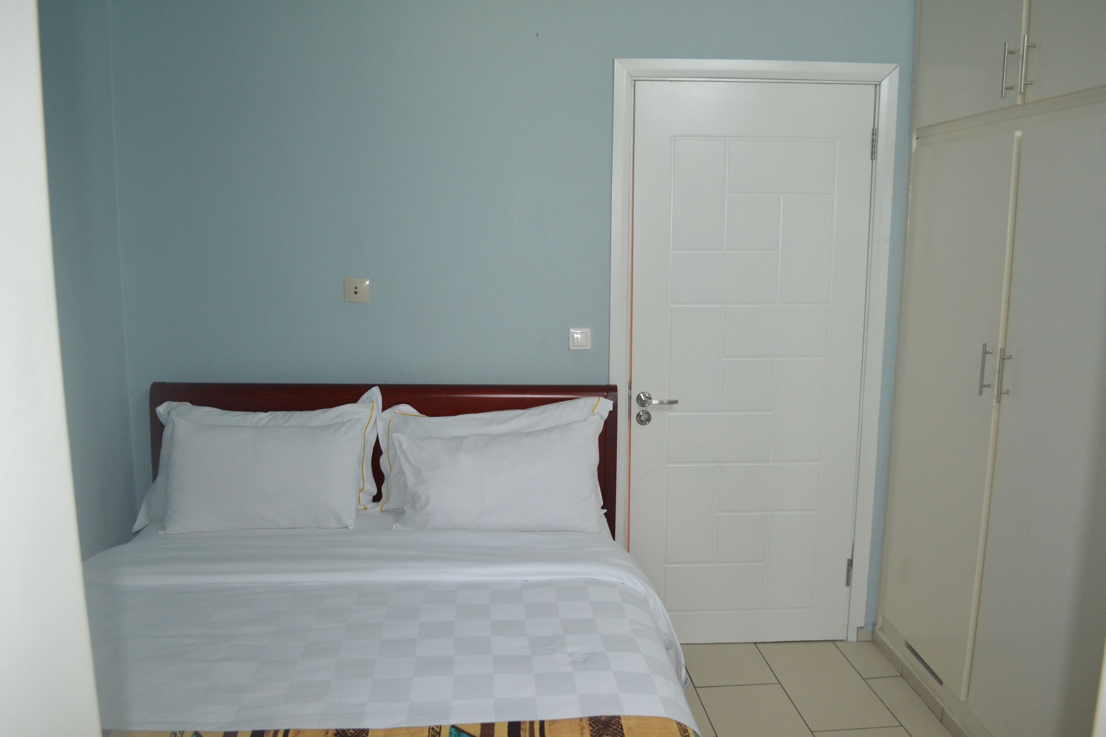 Un dormitorio con cama, una puerta y un armario.