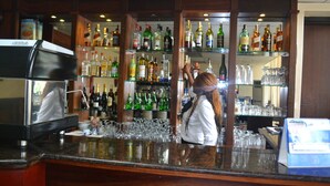 Un espace bar avec des étagères remplies de bouteilles d’alcool et de verres.