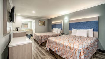 Habitación de hotel con dos camas, un escritorio, un televisor y un baño visible al fondo.