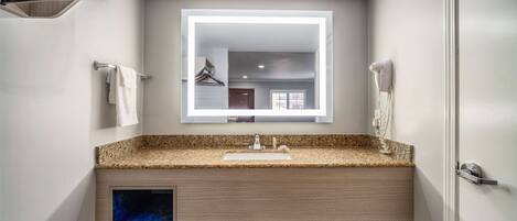 A modern bathroom with a granite countertop, a built-in sink, a towel rack, and a mirror.