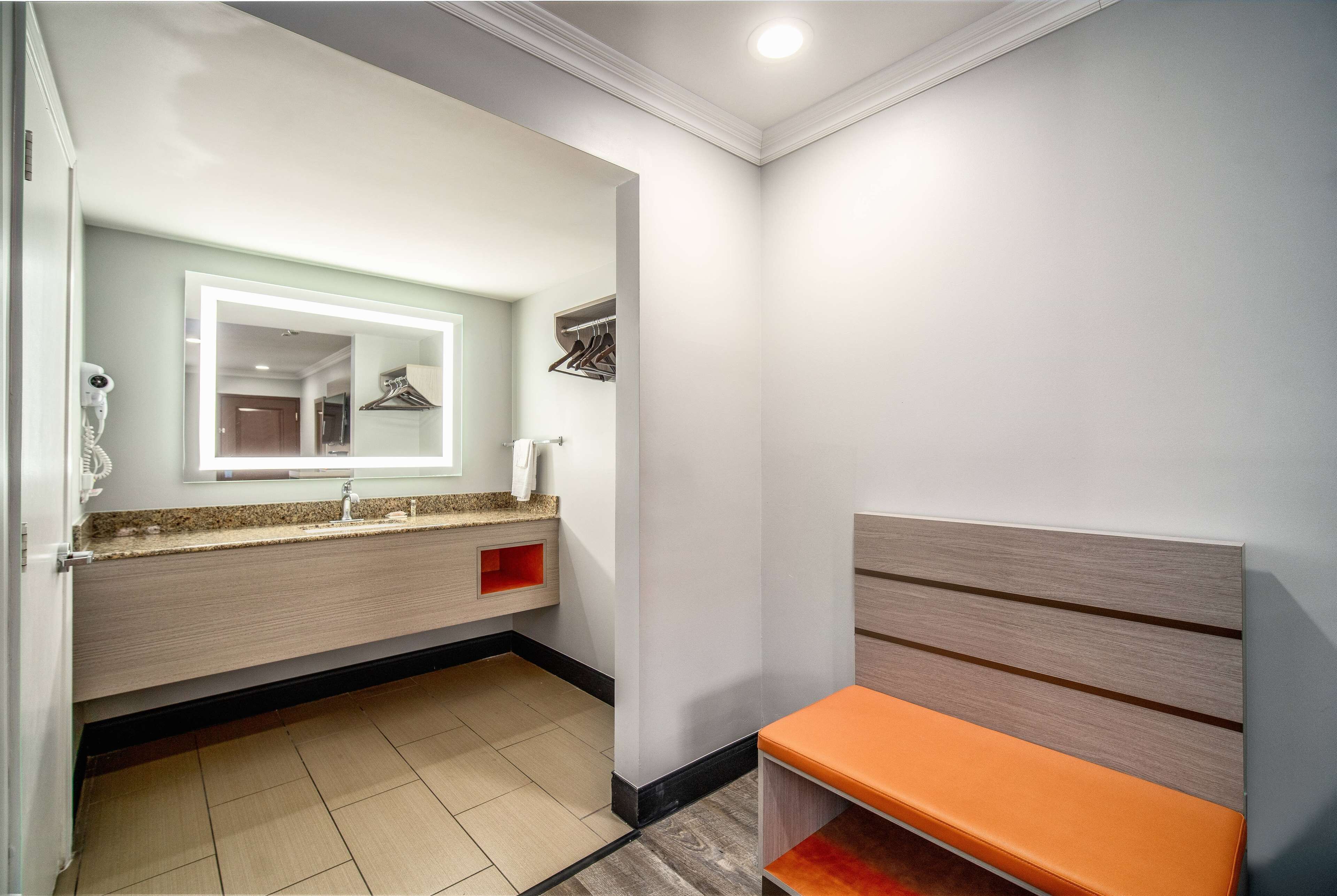 A modern bathroom with a vanity, mirror, and bench.